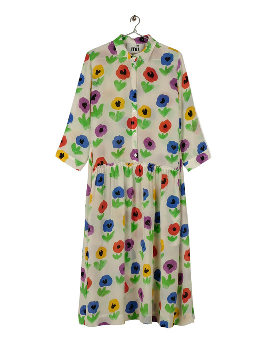 A handwoven silk dress with a floral pattern featuring multicolored pansies, displayed on a hanger against a white background.